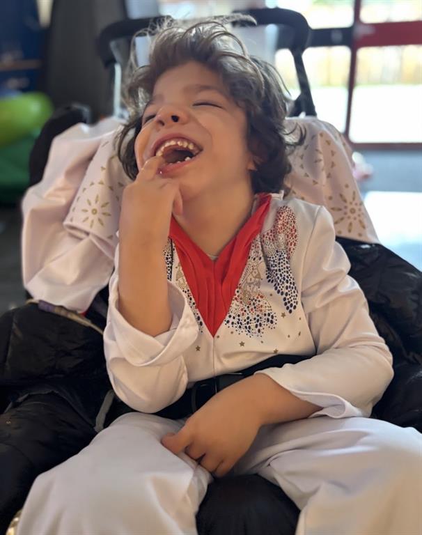 Young boy in white jump suit and red scarf smiling